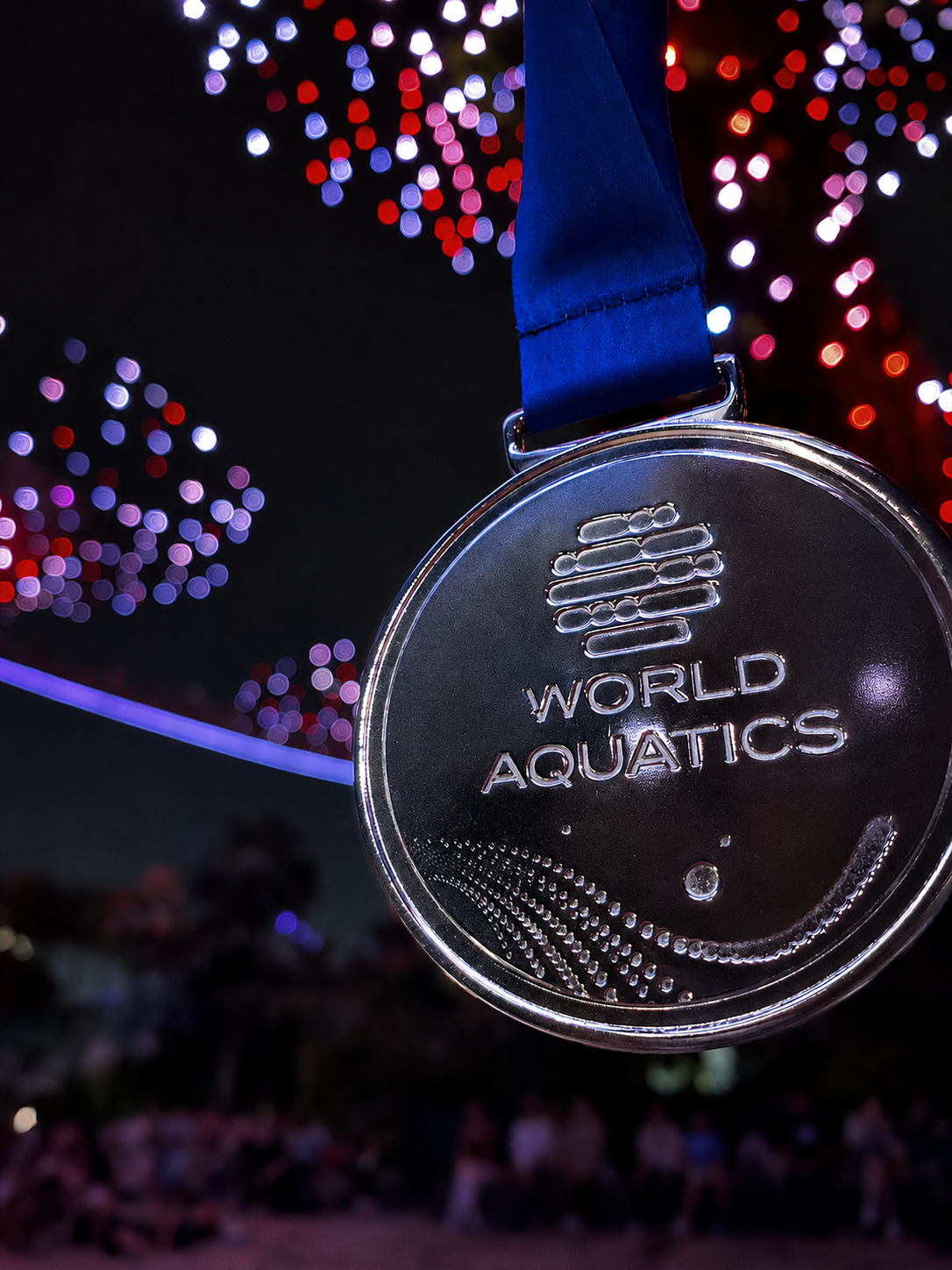 Medalla de World Aquatics colgando bajo fuegos artificiales en la noche