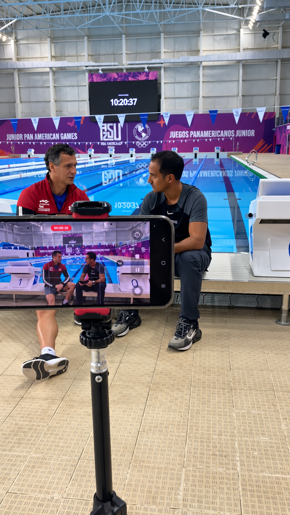 Conversación junto a la pileta en los Juegos Panamericanos Junior siendo grabada con un celular en trípode